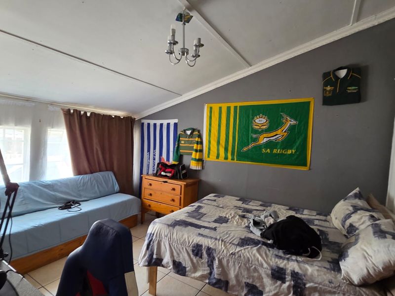 A bedroom featuring tiled flooring and a coved ceiling, currently utilized as a multi-purpose living and sleeping space.