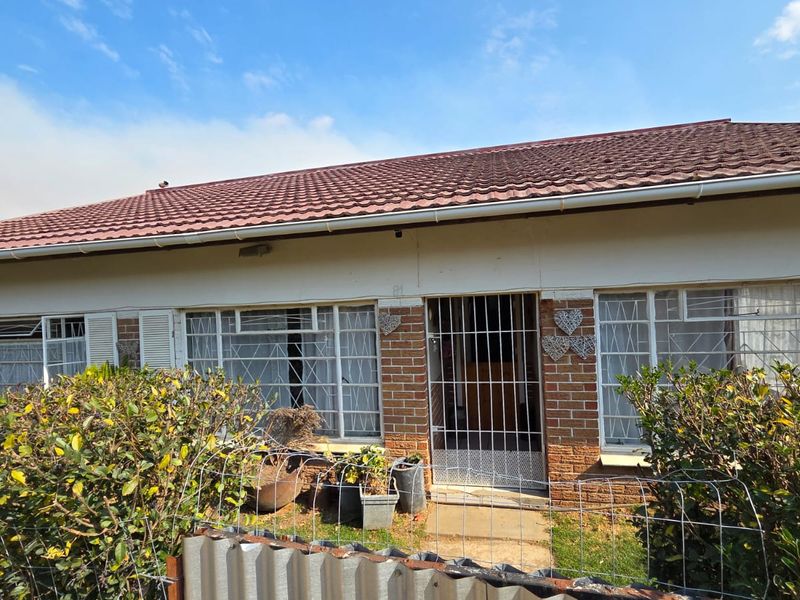 Front elevation of a single-story house featuring a tiled roof, brick facade, and security-fitted windows and entrance.