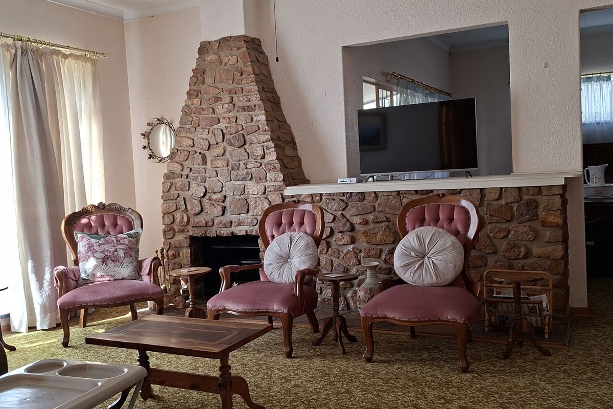 A living room featuring a prominent stone fireplace and feature wall, with large windows allowing natural light into the space.