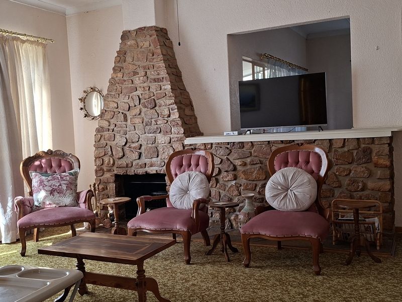 A living room featuring a prominent stone fireplace and feature wall, with large windows allowing natural light into the space.