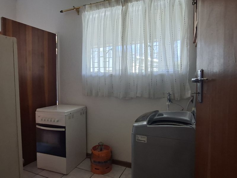A functional laundry area featuring tiled flooring and window security bars, providing a practical space for household utility tasks.