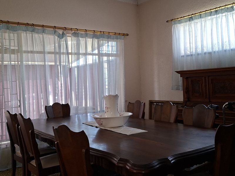 A dining room featuring a large sliding glass door leading to an outdoor area, with natural light and traditional window treatments.