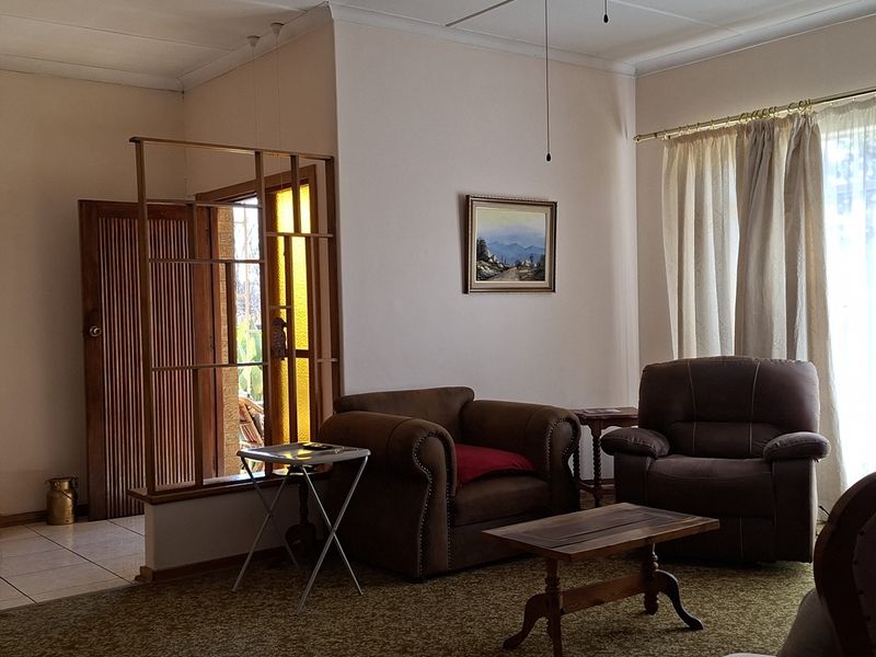 Spacious living room featuring a timber room divider, tiled and carpeted flooring, and access to the outdoors through a sliding glass door.