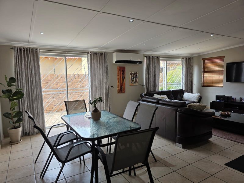 Spacious open-plan living and dining area featuring tiled floors, recessed lighting, and a split-system air conditioner with direct access to the exterior.