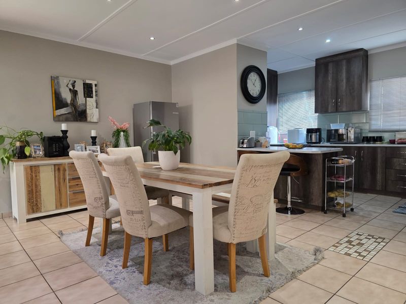 Open plan dining area and kitchen featuring tiled flooring, recessed lighting, and modern dark wood cabinetry with a functional kitchen island.