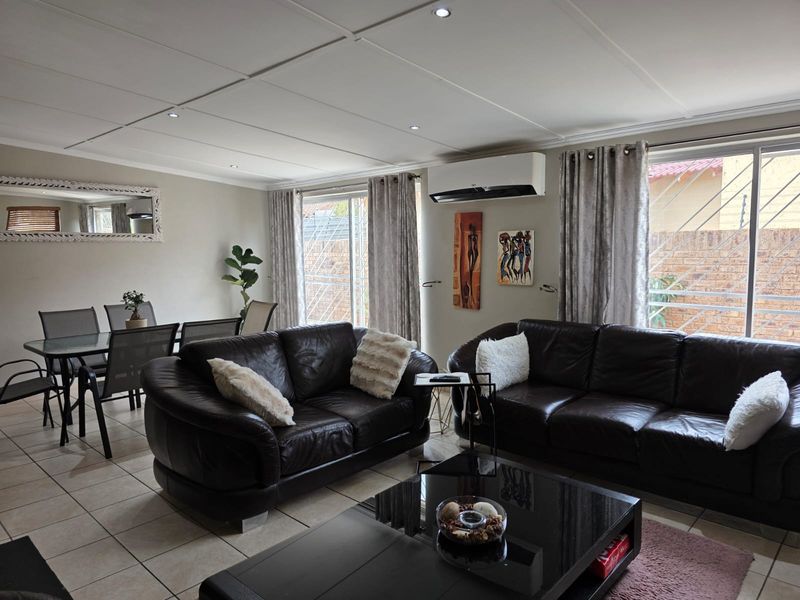 Spacious open-plan living and dining area featuring tiled floors, recessed lighting, and a wall-mounted air conditioning unit with access to the exterior.