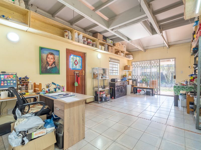 A functional utility space featuring exposed ceiling beams, ceramic tiled flooring, and direct access to the rear garden through a sliding security door.