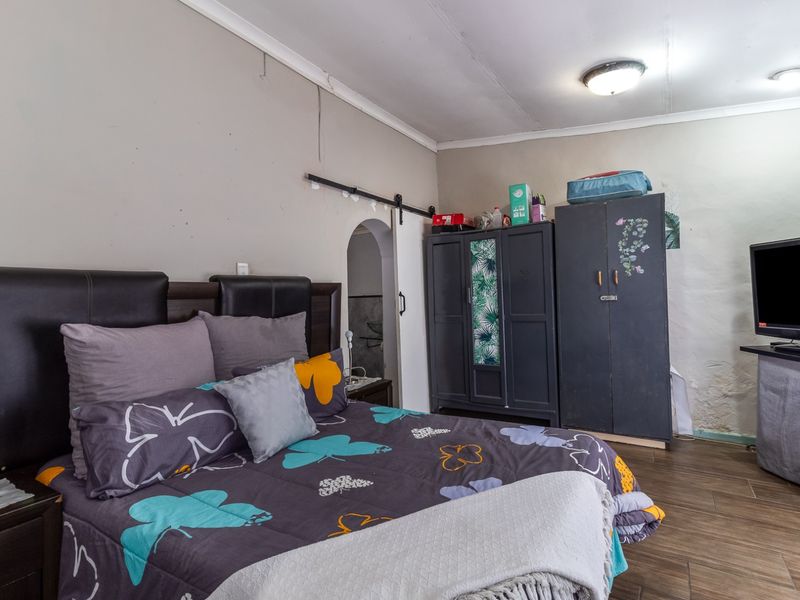 A bedroom featuring tiled flooring, a sliding barn door, and visible wall surface imperfections requiring maintenance or cosmetic repair.
