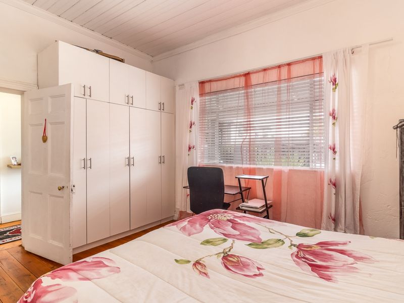 A bedroom featuring timber flooring, a timber panelled ceiling, and a large built-in wardrobe with ample storage space.