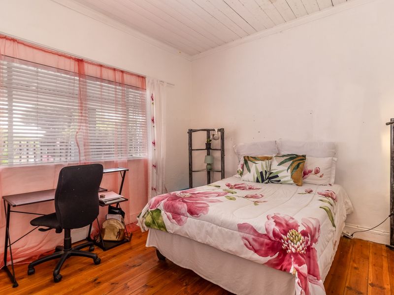 A bedroom featuring original timber flooring and a white-painted timber plank ceiling, offering a classic aesthetic with potential for cosmetic updates.
