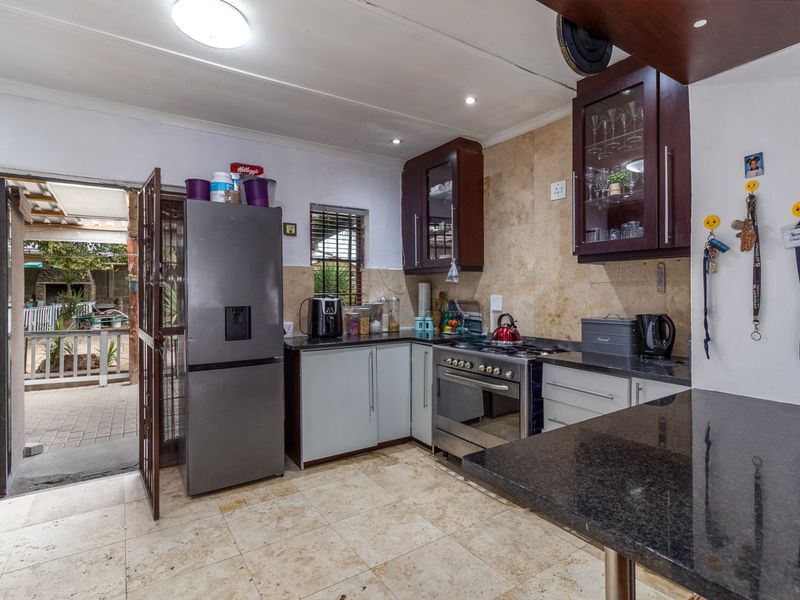 Functional kitchen featuring granite countertops, built-in oven with gas hob, and stone tiling, with direct access to an outdoor patio area.