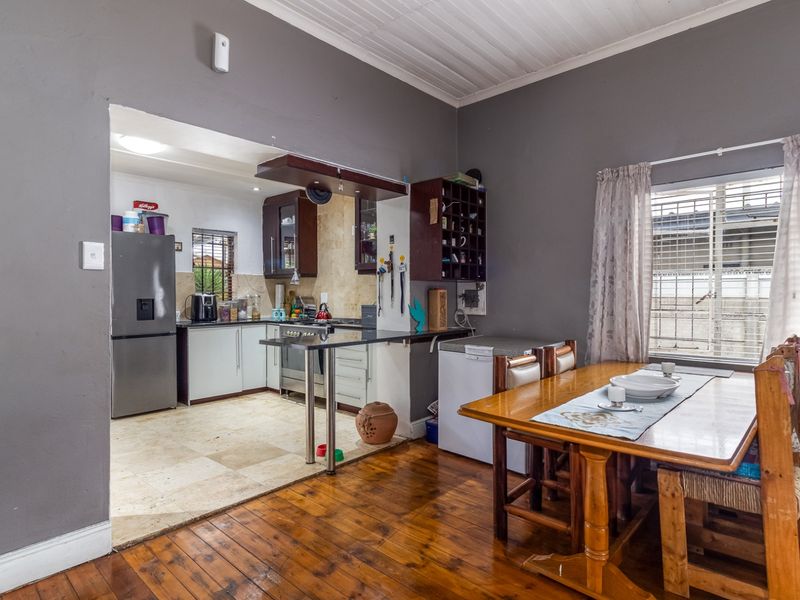Open-plan kitchen and dining area featuring timber flooring, stone countertops, and a functional kitchen layout with built-in cabinetry and gas hob.