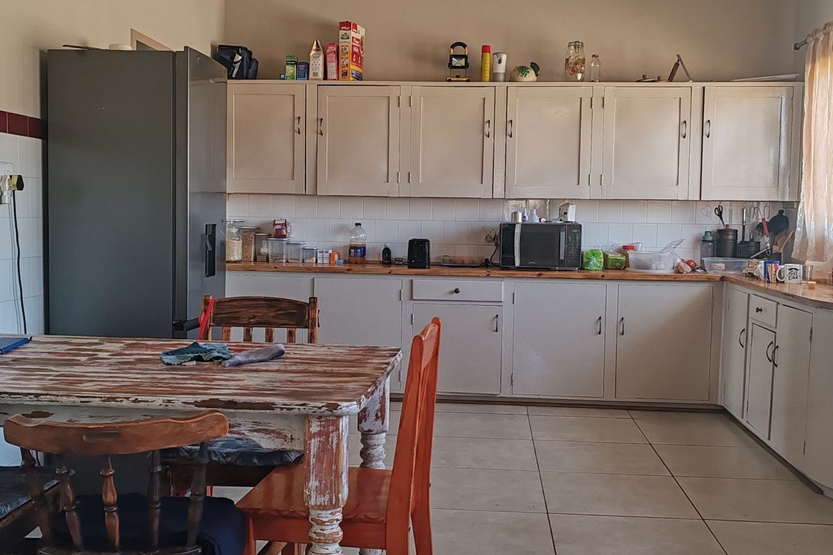 A functional kitchen featuring built-in cabinetry, tiled splashbacks, and tiled flooring, offering a practical layout with a freestanding stove and ample counter space.