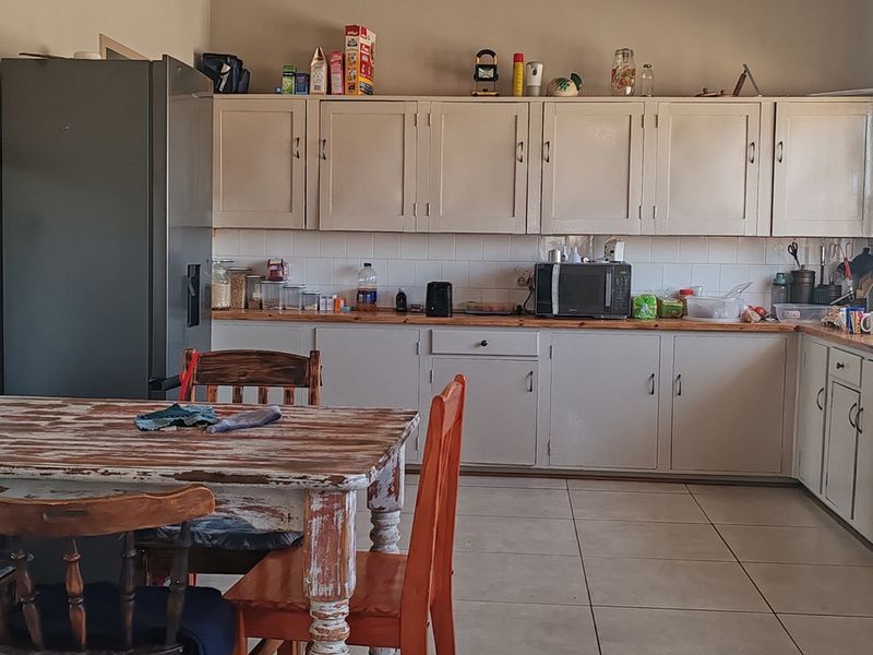 A functional kitchen featuring built-in cabinetry, tiled splashbacks, and tiled flooring, offering a practical layout with a freestanding stove and ample counter space.