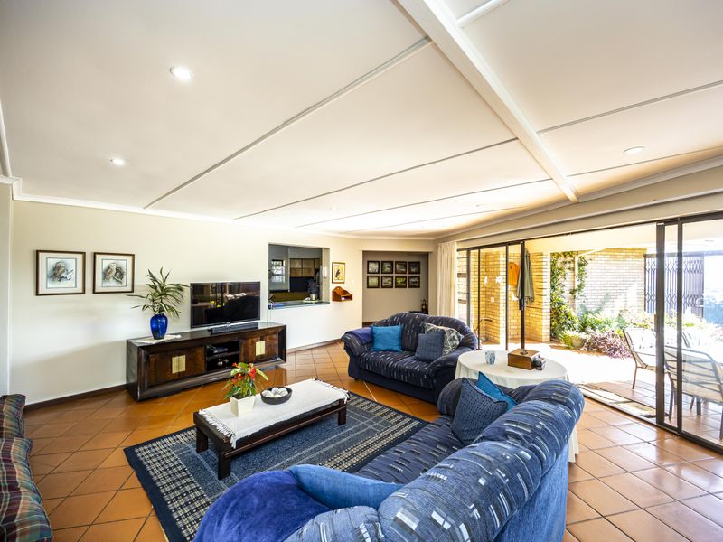 Spacious living room featuring terracotta floor tiles, exposed ceiling beams, and large sliding glass doors providing seamless access to the outdoor patio area.