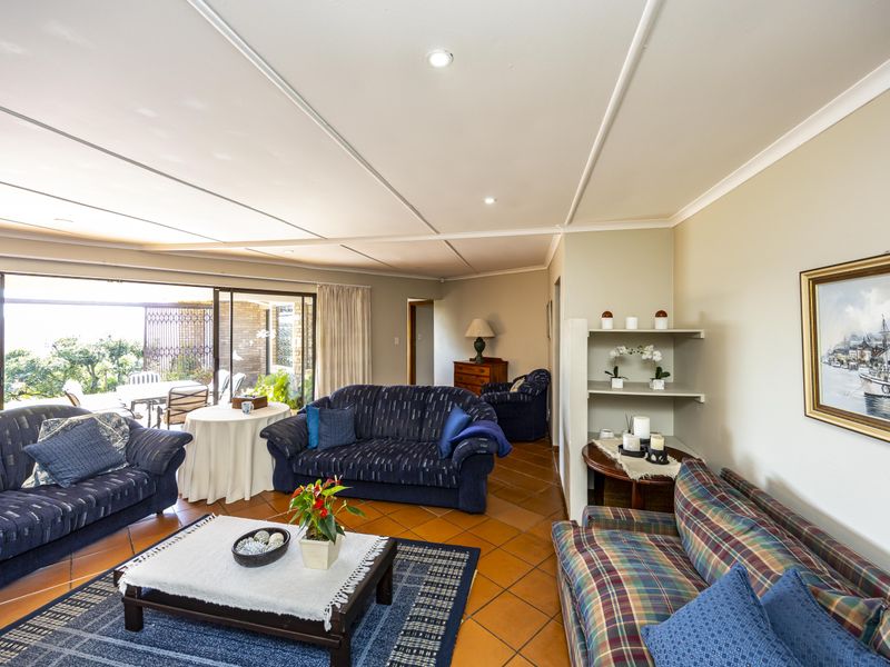 Spacious living room featuring terracotta floor tiles, recessed lighting, and large sliding glass doors providing seamless access to the outdoor patio area.