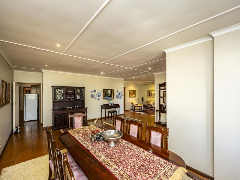 Spacious open-plan dining and living area featuring tiled flooring, coved ceilings, and recessed lighting, creating a connected and functional living space.