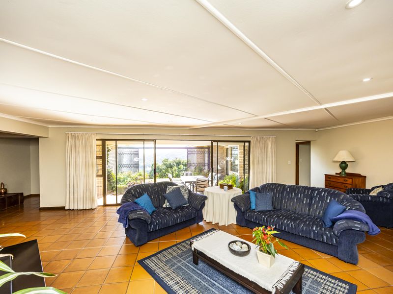 Spacious living room featuring terracotta floor tiles, recessed lighting, and large sliding glass doors providing access to the outdoor patio area.