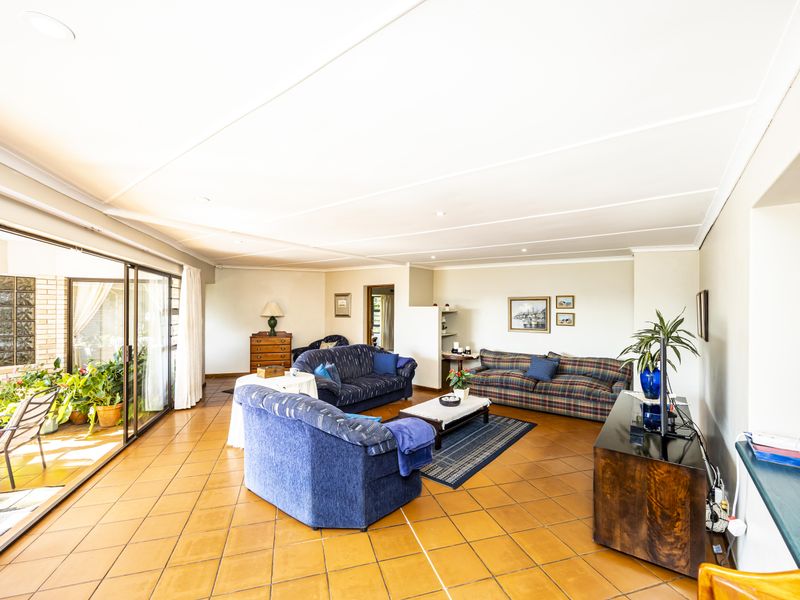 Spacious living room featuring terracotta floor tiles, recessed lighting, and large sliding glass doors providing access to an outdoor patio area.