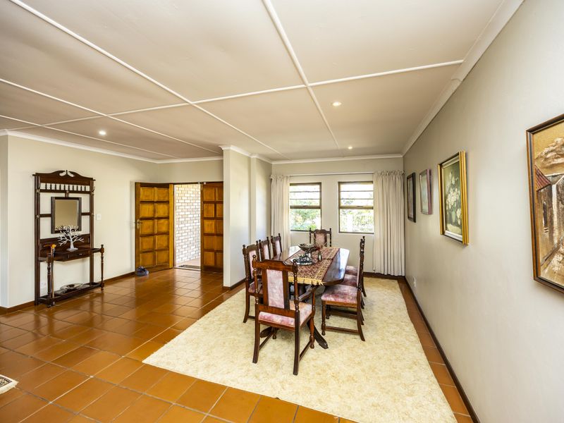 Spacious dining room featuring terracotta floor tiles, a unique grid-pattern ceiling, and direct access to adjacent living areas through wooden double doors.