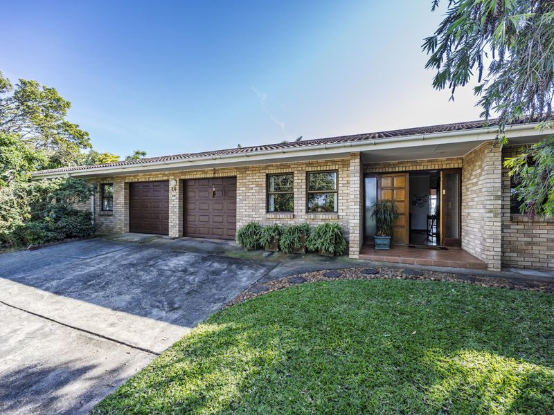 Front elevation of a single-story brick house featuring a double garage, concrete driveway, and a covered entrance with timber door.