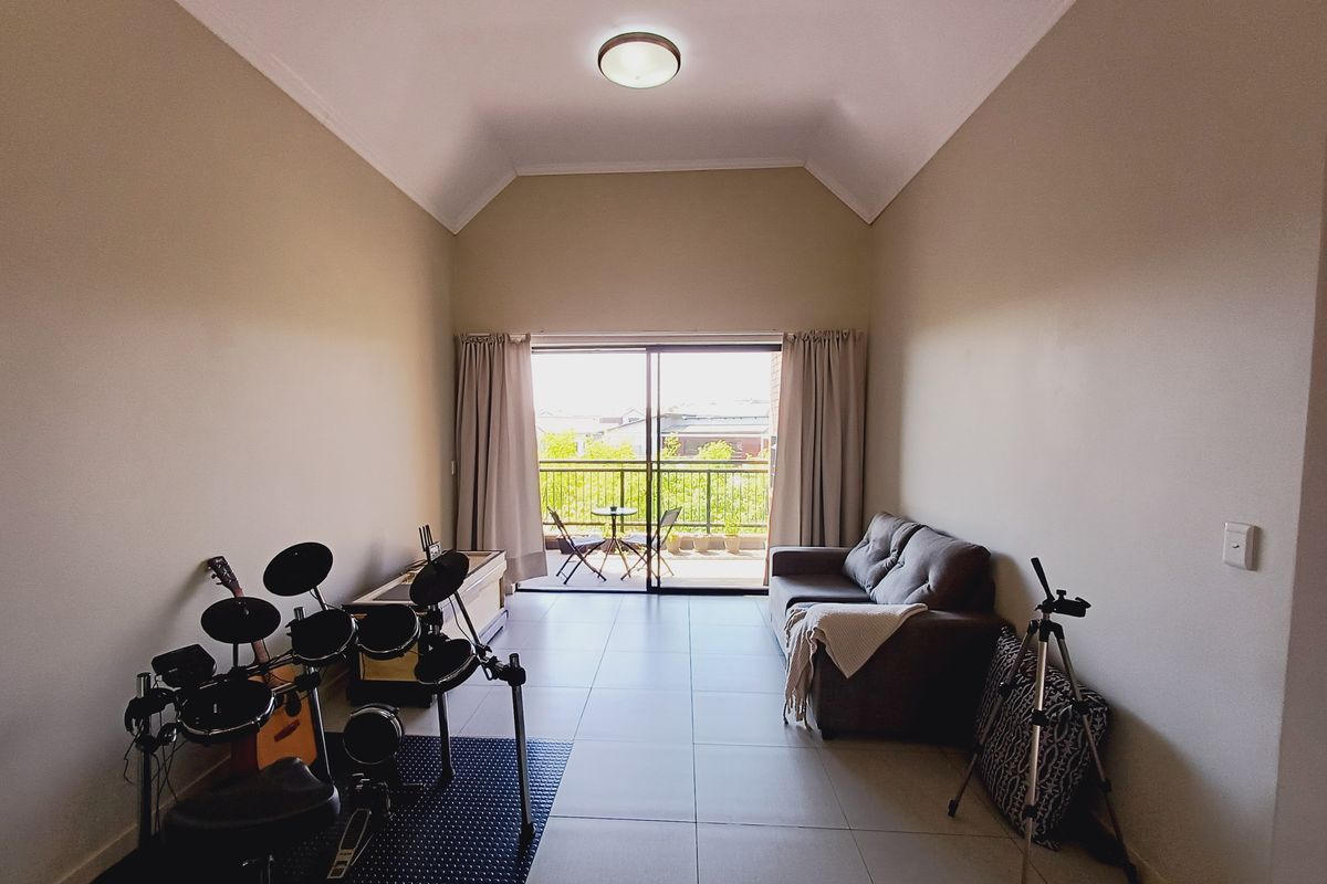 Spacious living room featuring high vaulted ceilings, neutral tiled flooring, and large sliding glass doors leading to a private balcony.