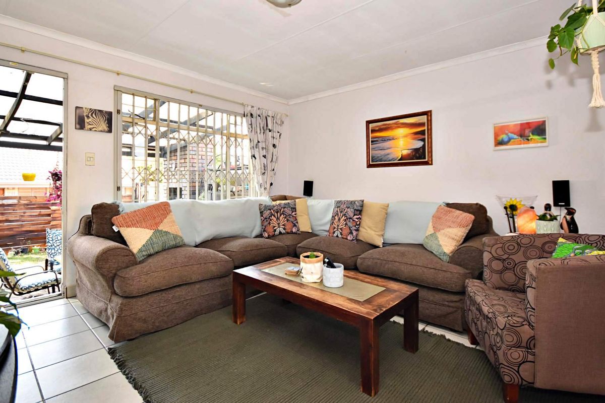 A living room featuring tiled flooring, a sliding door leading to an outdoor area, and window security bars.