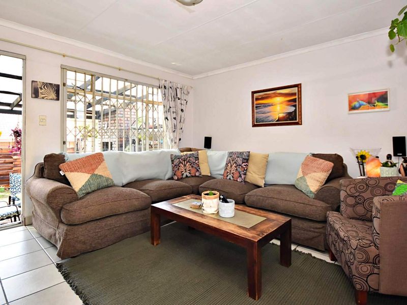 A living room featuring tiled flooring, a sliding door leading to an outdoor area, and window security bars.
