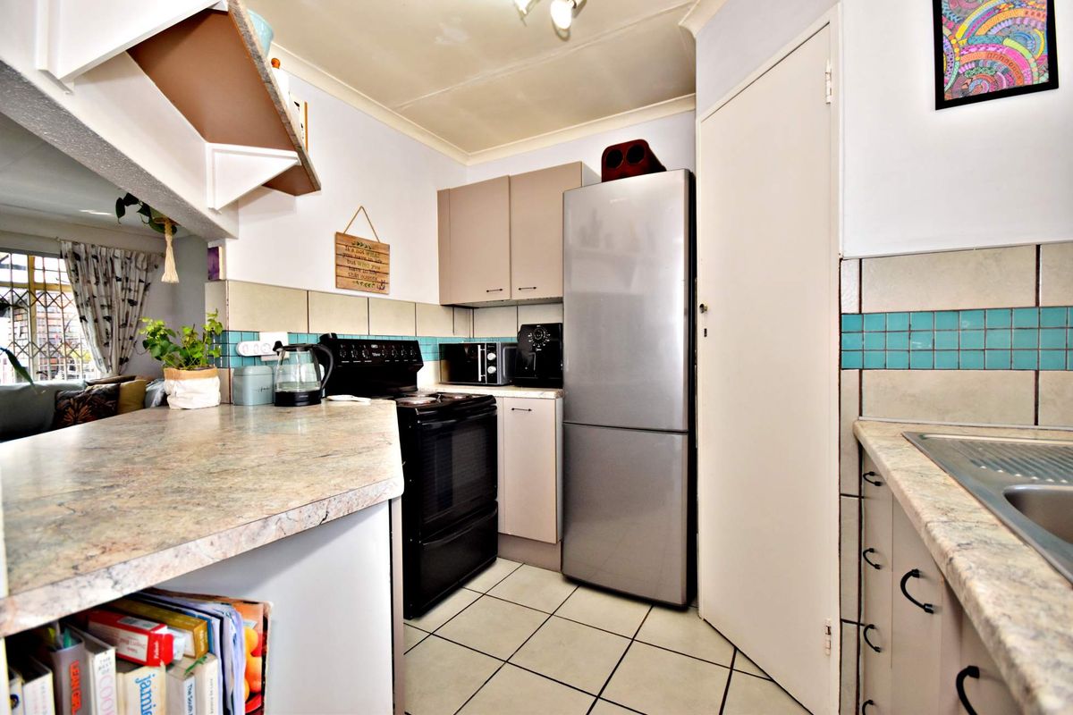 Compact kitchen featuring laminate countertops, tiled backsplash, built-in cabinetry, and ceramic floor tiles, offering a functional layout for daily meal preparation.