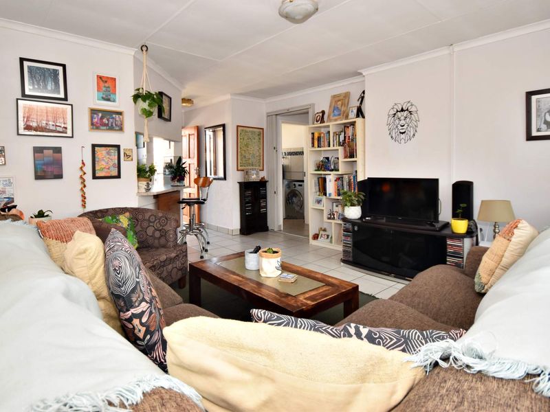 Open plan living area featuring tiled flooring and a breakfast bar, with a view through to the laundry area.