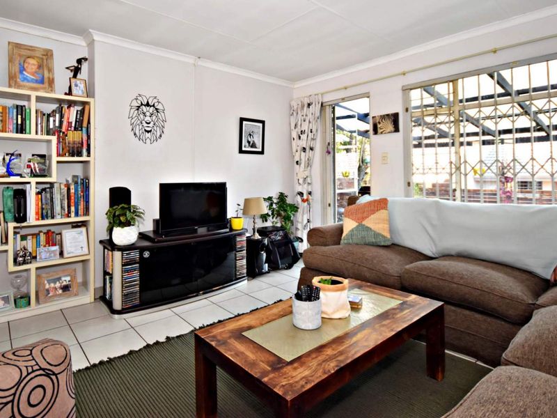 A comfortable living room featuring tiled flooring and a sliding glass door with security gate, providing access to the outdoor area.