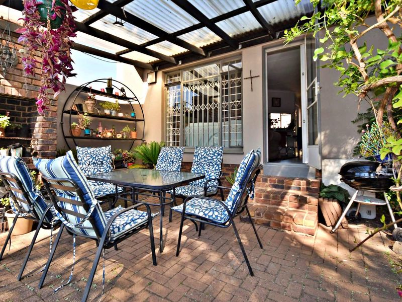 Covered outdoor patio featuring brick paving, a built-in brick fireplace, and direct access to the interior through a security-fitted door.