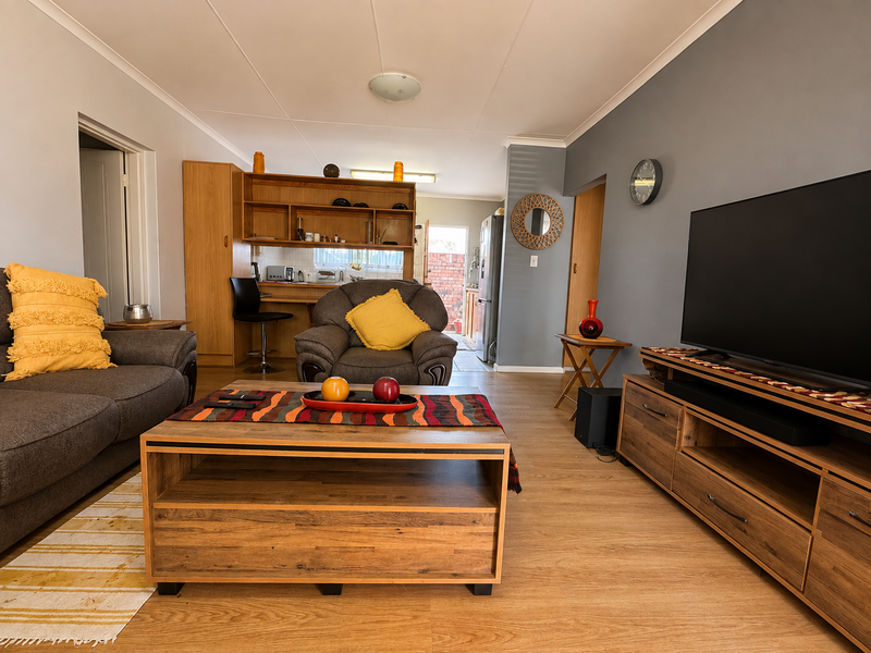 Open plan living area featuring laminate flooring, coved ceilings, and built-in shelving, creating a functional and connected space.