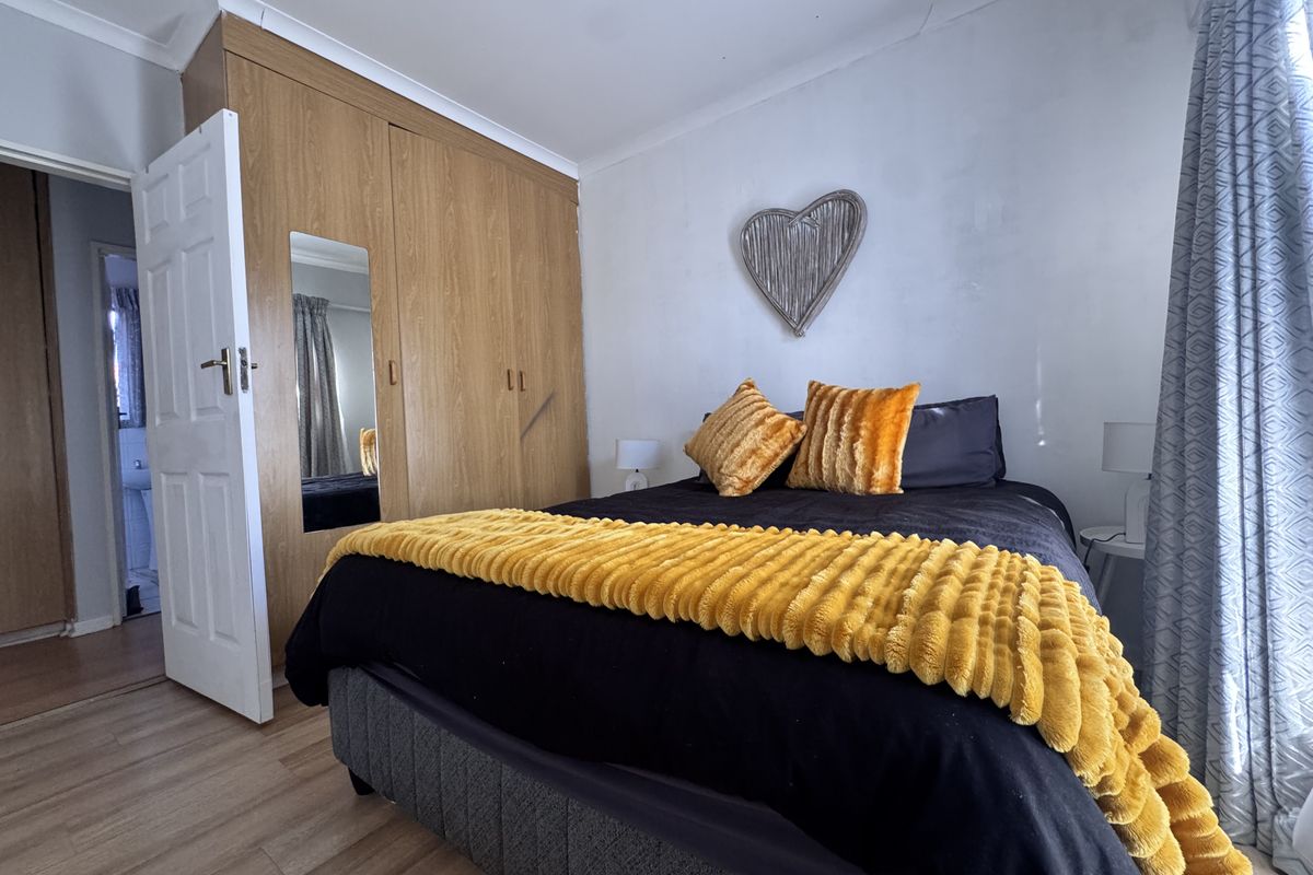 A bedroom featuring built-in wooden wardrobes, laminate flooring, and coved ceilings, offering a functional space with potential for cosmetic updates.