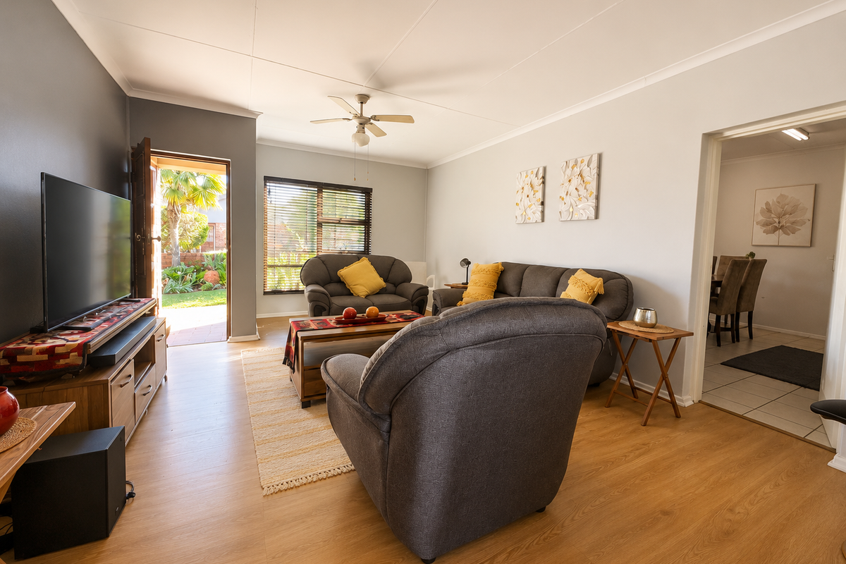 A well-maintained living room featuring laminate flooring, a ceiling fan, and direct access to an outdoor patio area.