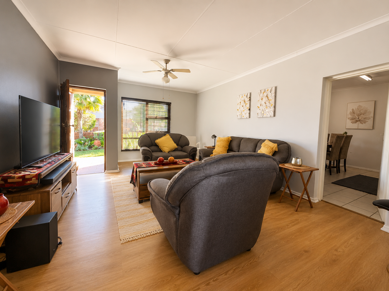 A well-maintained living room featuring laminate flooring, a ceiling fan, and direct access to an outdoor patio area.