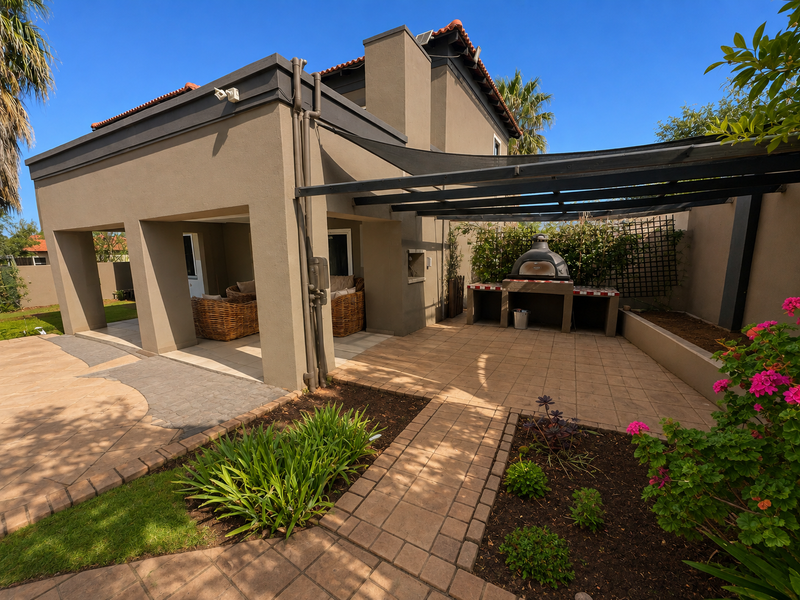 Covered patio area featuring a built-in pizza oven, paved flooring, and a shade sail structure, ideal for outdoor entertaining.