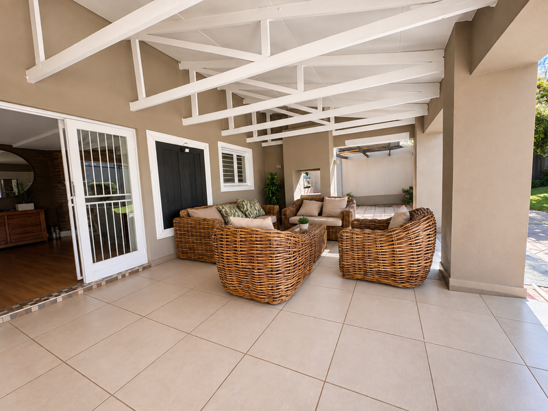 A spacious covered patio featuring tiled flooring and exposed white timber roof trusses, providing a seamless transition to the interior living space.