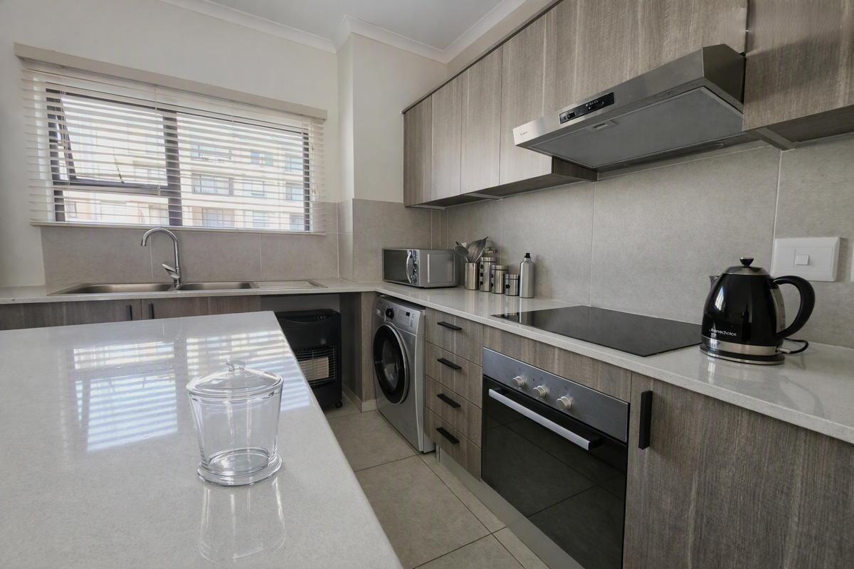 Modern kitchen featuring sleek wood-grain cabinetry, stone countertops, integrated appliances, and a functional layout with ample storage and a built-in oven and hob.