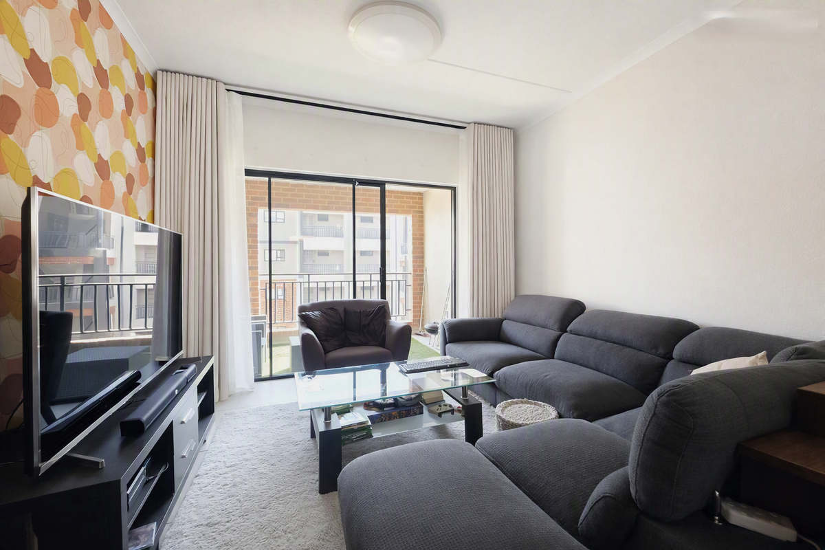 A well-lit living room featuring a large sliding glass door leading to a balcony, complemented by patterned wallpaper and neutral finishes.