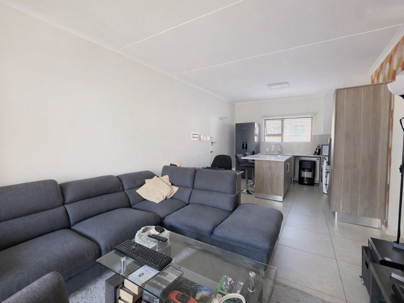 Open-plan living area featuring a modern kitchen with a central island, tiled flooring, and neutral finishes throughout.