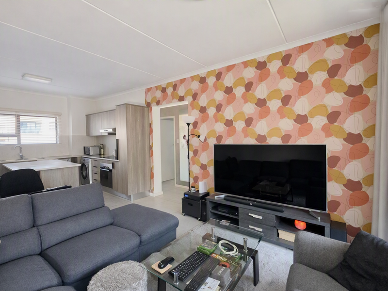 Open-plan living area featuring a modern kitchen with built-in cabinetry, integrated appliances, and a distinctively patterned feature wall.