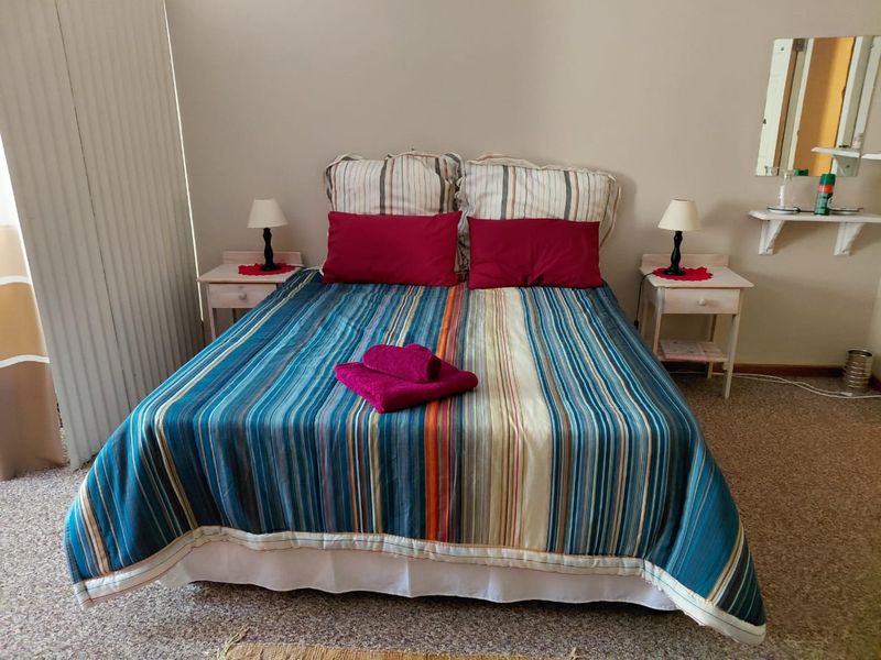 A functional bedroom featuring carpeted flooring, a wall-mounted shelf, and a sliding door, providing a simple and practical living space.