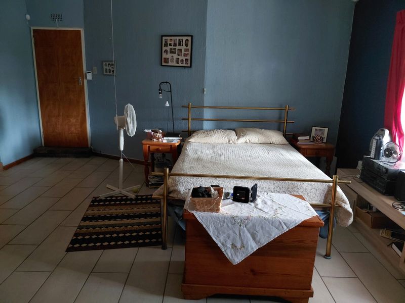 A spacious bedroom featuring tiled flooring and a solid wood door, offering a functional layout ready for modern updates.