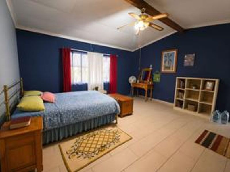 Spacious bedroom featuring tiled flooring, a ceiling fan, and an exposed ceiling beam, offering a comfortable and functional living space.