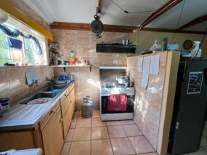 A dated kitchen featuring tiled splashbacks, built-in cabinetry, and a freestanding stove, offering significant potential for modernization and renovation.