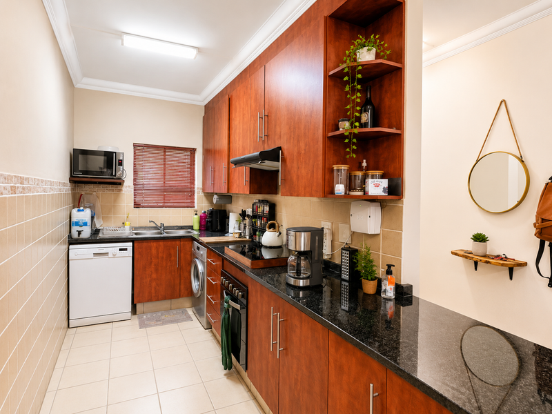 A functional kitchen featuring warm-toned wooden cabinetry, granite countertops, a tiled backsplash, and integrated appliances, offering a practical and well-maintained workspace.