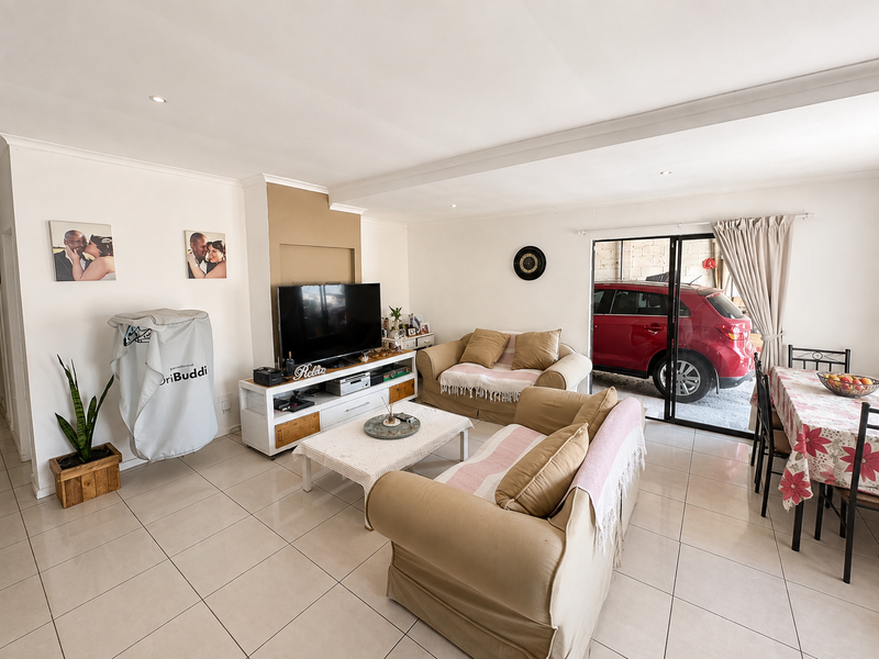 An open-plan living and dining area featuring neutral tiled flooring, recessed lighting, and a sliding glass door providing access to the exterior.