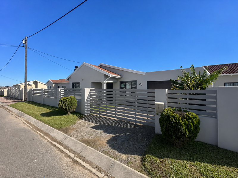 Front view of a well-maintained single-story house featuring a modern horizontal slat gate, perimeter wall, and a neat front garden.