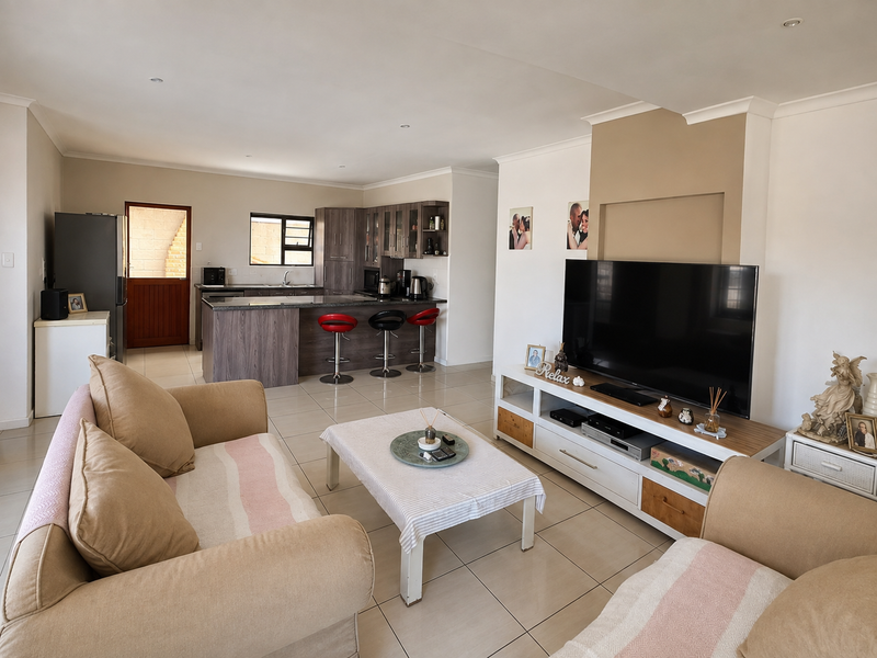 Spacious open-plan living area featuring a modern kitchen with island seating, tiled floors, and a central fireplace feature wall.